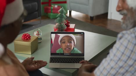 Feliz-Pareja-Afroamericana-De-Edad-Avanzada-En-Videollamada-En-Una-Computadora-Portátil-Con-Su-Nieto-En-Navidad