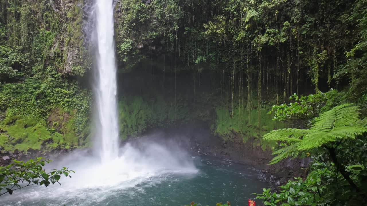 The cascading water from the Fortuna Waterfall into the lake below in a wonderful tropical jungle setting in Costa Rica