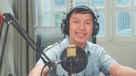 Over Shoulder View, Asian Kid Girl Host Record Podcast Use Microphone Wear Headphone Interview Young Boy Guest Conversation In Her Home Studio, He Smiles And Looking At Camera