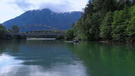 A-jet-boat-sets-out-on-a-river-and-crosses-under-a-bridge-in-Norther-British-Colombia,-Canada