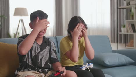 asian children with joystick game playing video games and disappointed