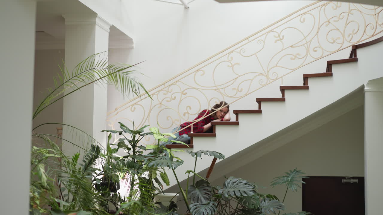 una mujer joven con un colapso emocional yace en la escalera. una mujer deprimida sufre de un trastorno de salud mental en casa. necesita tratamiento psicológico