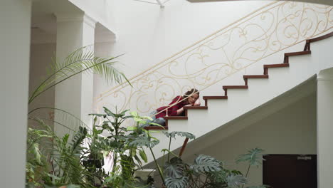 young woman with emotional breakdown lies on staircase. depressed lady suffers from mental health disorder at home. psychological treatment need