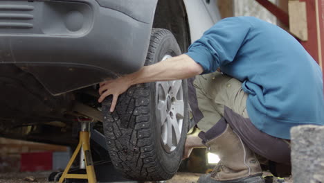 Man-does-wheel-fitment-after-changing-to-snow-tyres-using-impact-wrench,-closeup