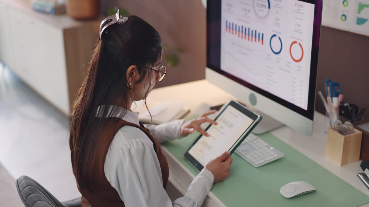 Woman Analyzing Data on Tablet at Desk