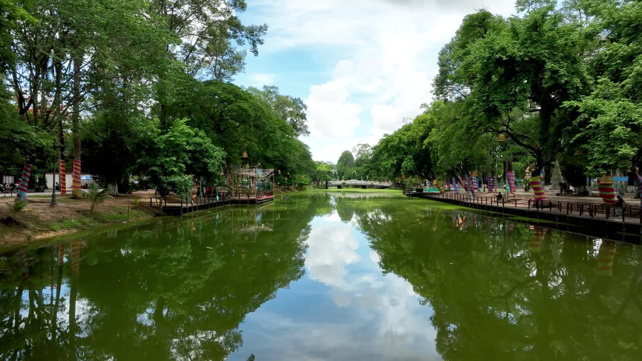City traffic passing past urban river greenery, Siem Reap waterways