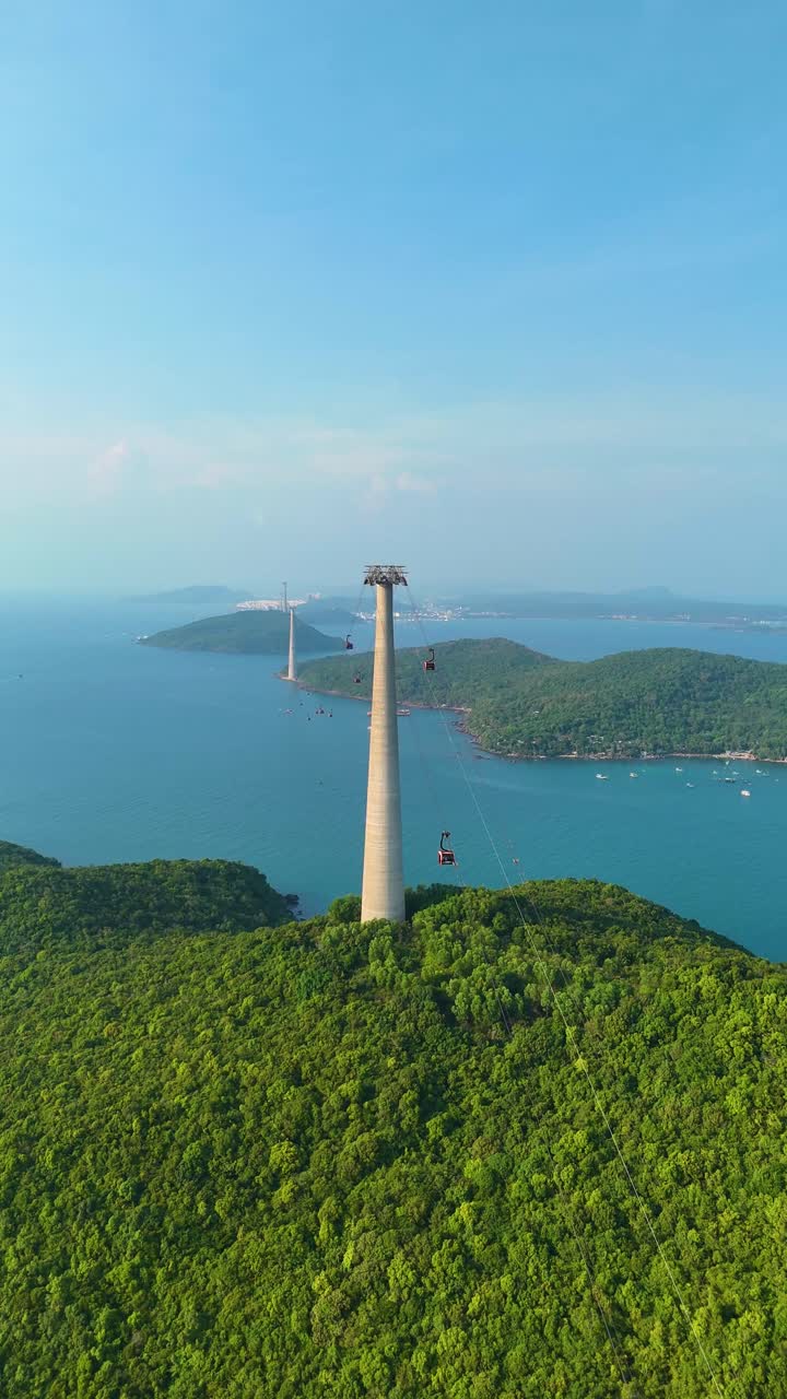 Vertical drone shot of the World's longest three-rope cable car stretching over lush green islands in Phu Quoc, Vietnam.