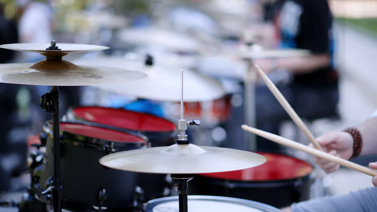 Close up of man playing red drums outside