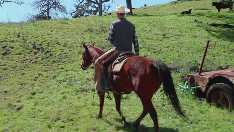 As-a-1900s-tow-truck-sits-in-the-background,-a-cowboy-rides-his-horse-through-the-frame