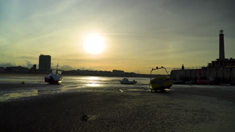 silhouette of a harbour with boats on the beach during sunset golden hour