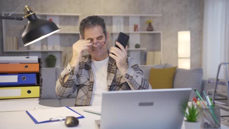 mature man working in home office talking on the phone and is happy.