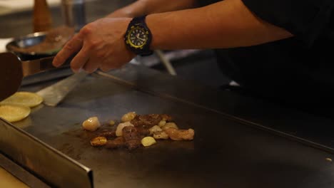 chef expertly prepares food on hot teppanyaki grill.