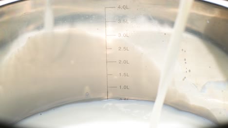pouring milk into a metal container pouring milk into a metal container preparation of food based on cows milk slow motion