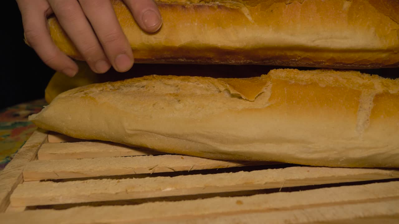 Uomo che prepara e impila più pagnotte di pane galiziano su un tagliere di legno.