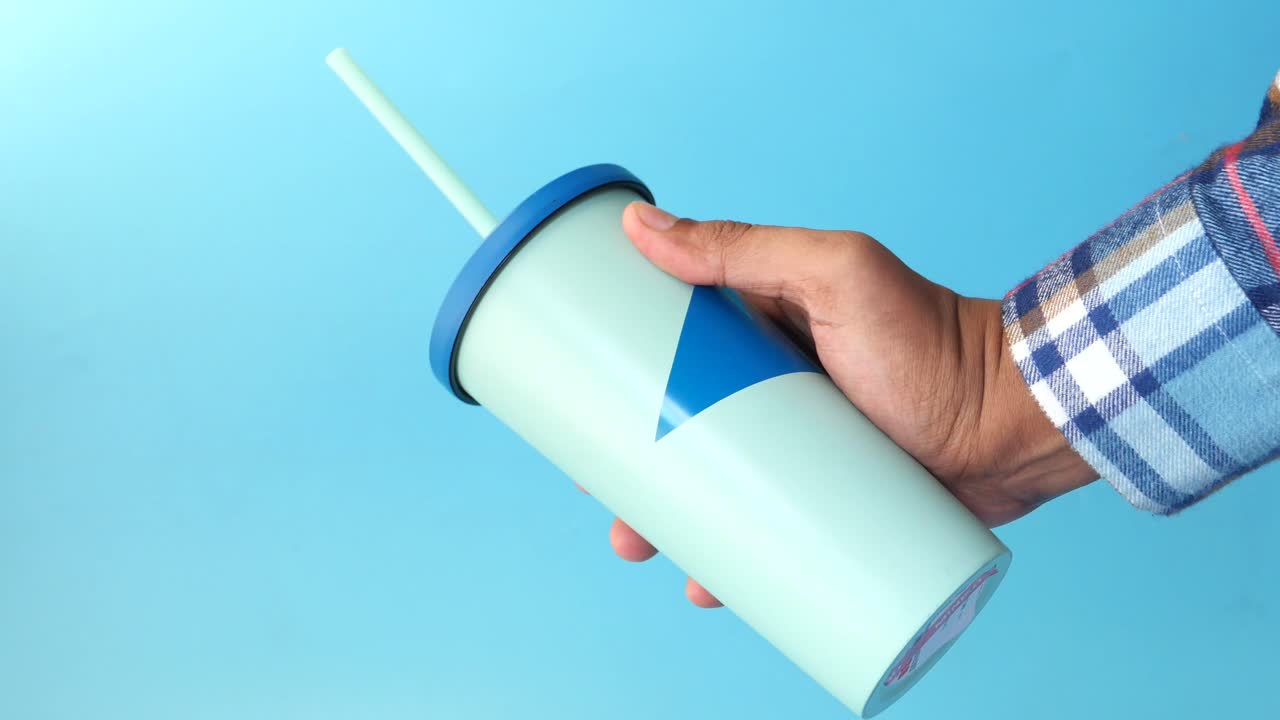 persona sosteniendo un vaso verde menta con un diseño azul