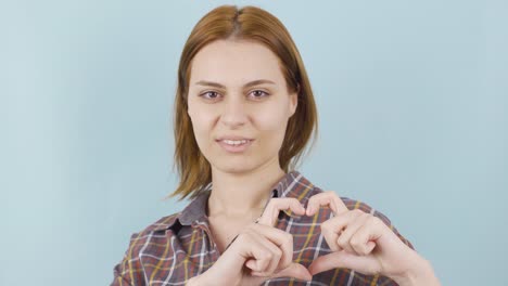 loving sympathetic woman making heart sign at camera.