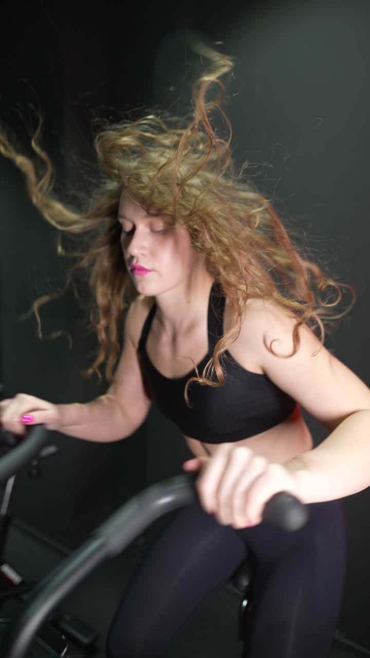mujer haciendo ejercicio en bicicleta con el cabello azotado por el viento