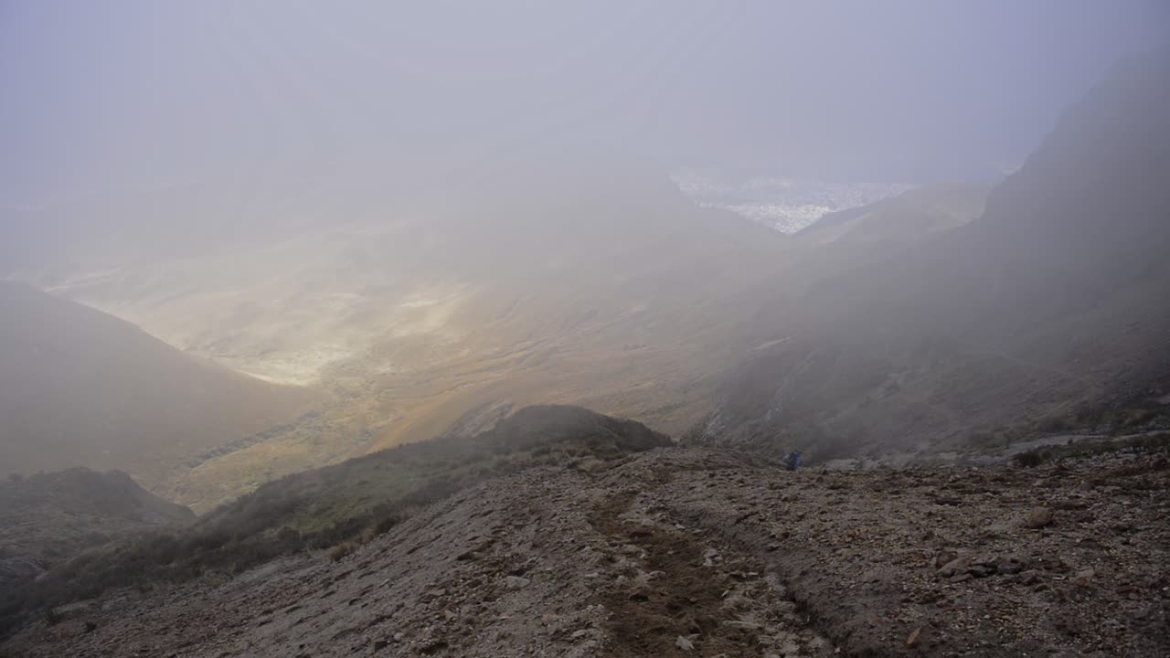 Landscape view of a man running down a volcanic mountainside, on a foggy and moody day, Ecuador