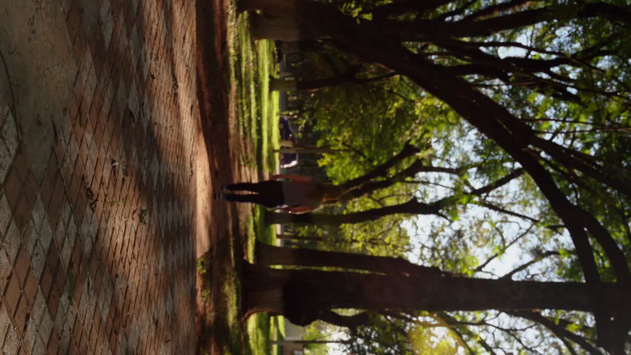 Young woman walking in a park with many trees around