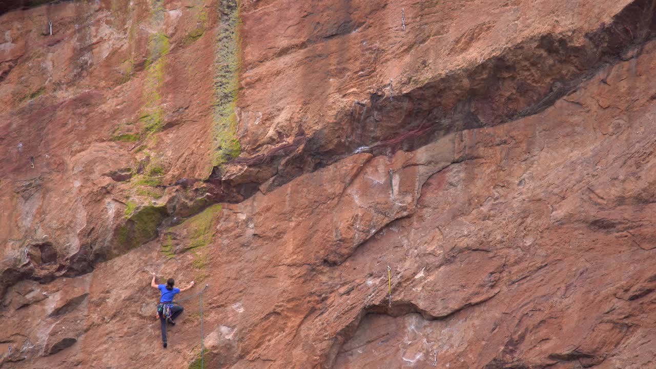 Woman climbing a steep rock using climbing gear