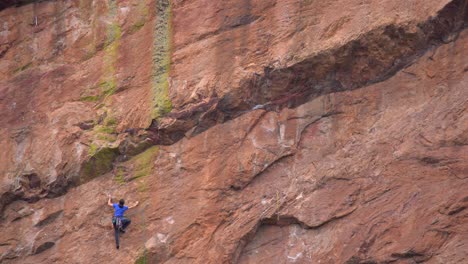 woman climbing a steep rock using climbing gear