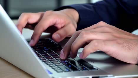 close-up of a businessman's hands typing on a laptop keyboard