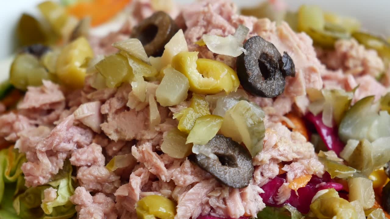 Colher escolher salada de atum de uma tigela na mesa