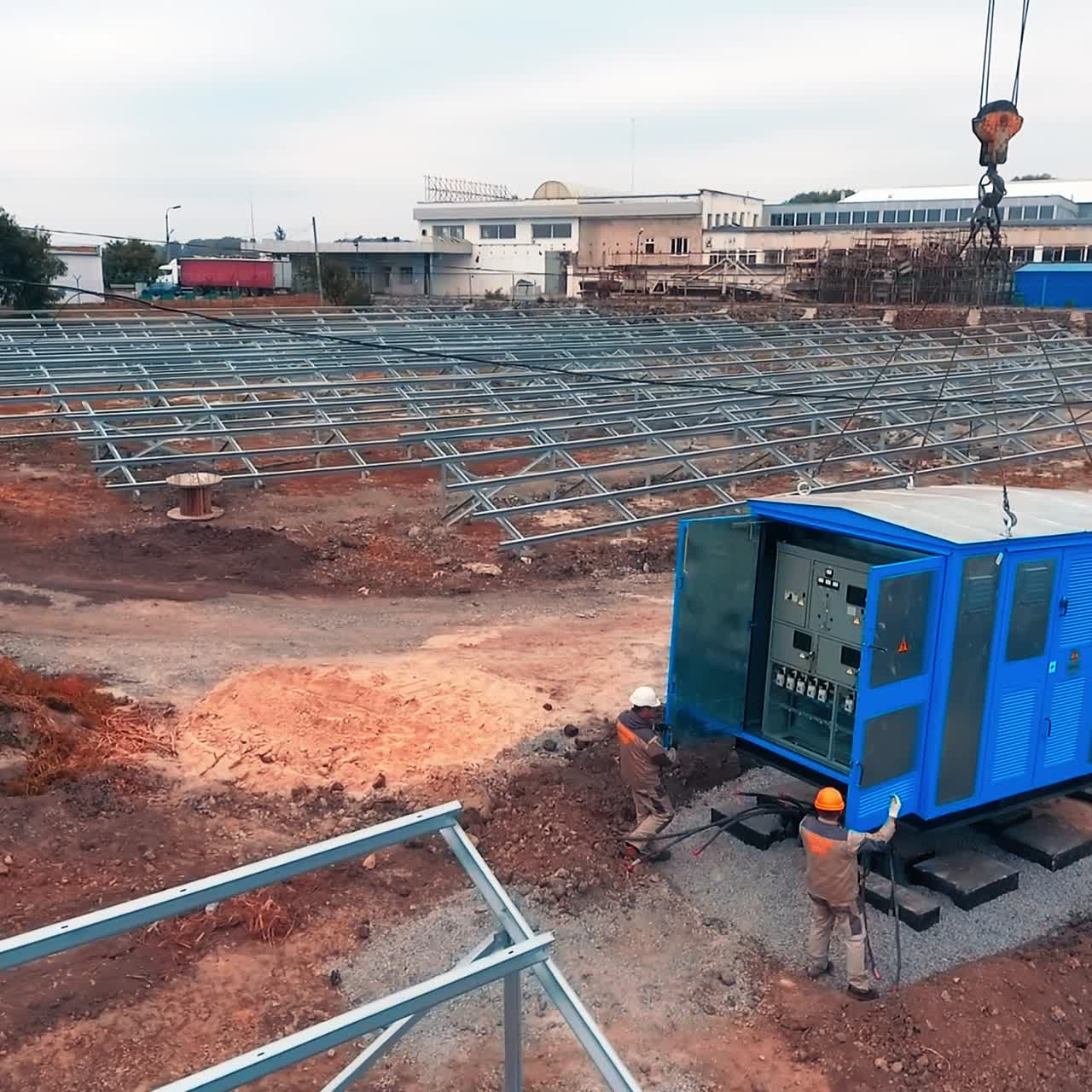 Big area covered with the metal constructions all over the place. Worker try to set the metal booth with technical equipment with the help of crane