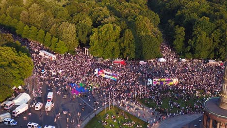 trucks,-Great-aerial-top-view-flight-CSD-Pride-Parade-2023-city-Berlin-Germany-Summer-evening-Victory-Column