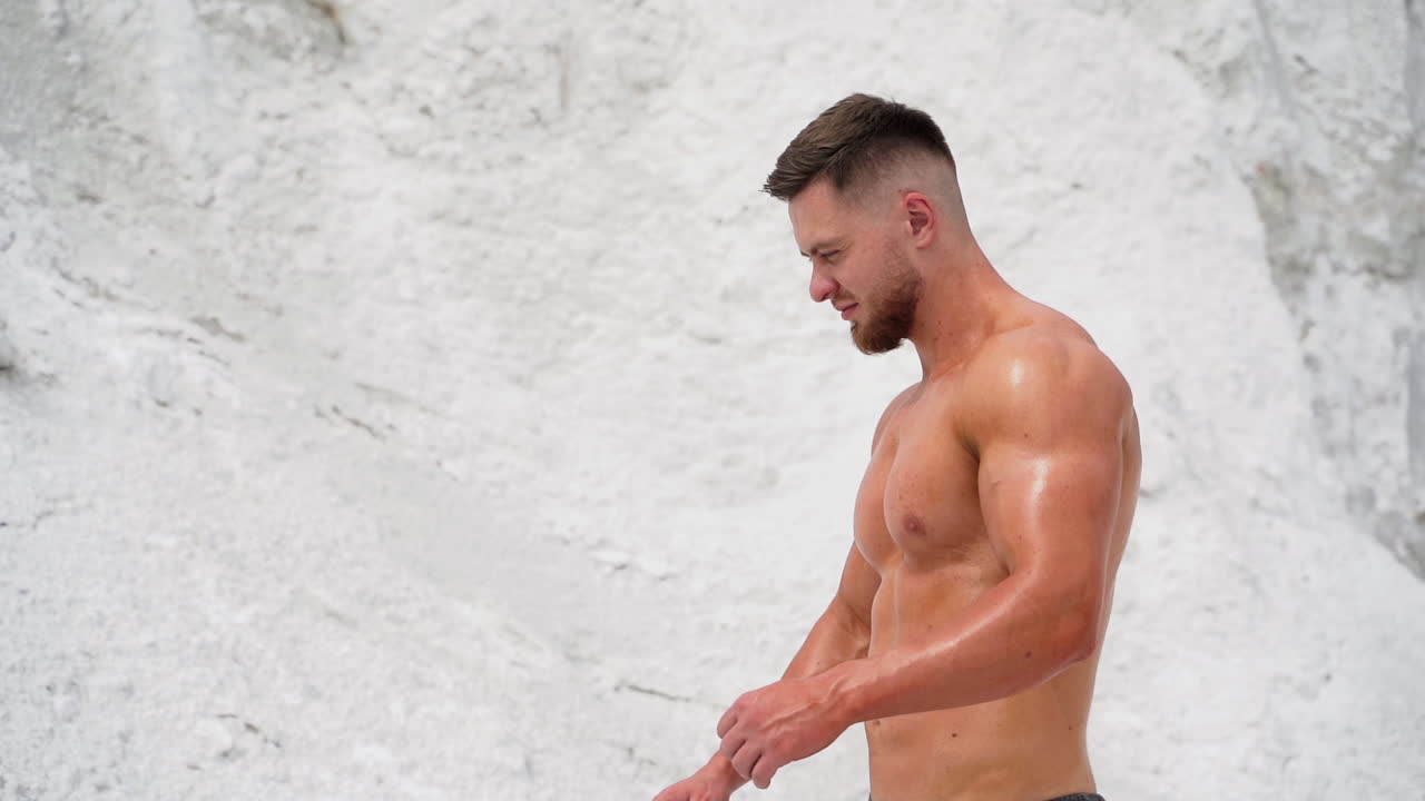 Muscular sportsman without t-shirt in nature. Back-side view of a strong man on white mountain background. Close-up.