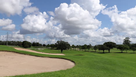 Landscape-of-large-golf-course-showing-green-grass-and-sandpits-and-trees-in-the-distance-of-the-golf-course