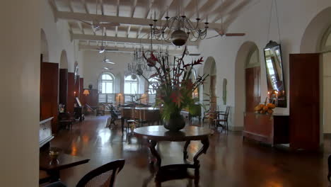 a elegant colonial hotel lounge with vintage furniture, flower arrangement and warm natural light reflecting on polished wood floor