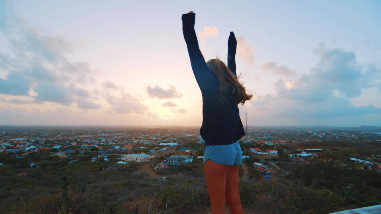 niña extendiendo los brazos, vista del amanecer sobre curacao, caribe, cámara lenta