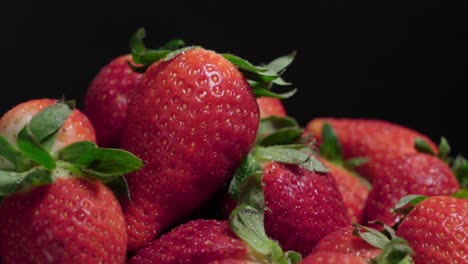 primer plano giratorio de fresas frescas, aislado sobre fondo negro