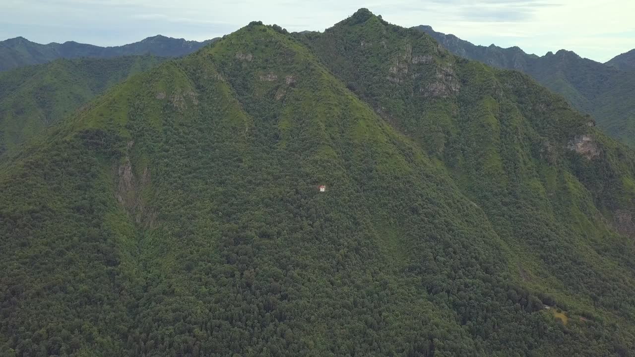 una sola capilla de iglesia blanca en medio de una montaña verde, italia