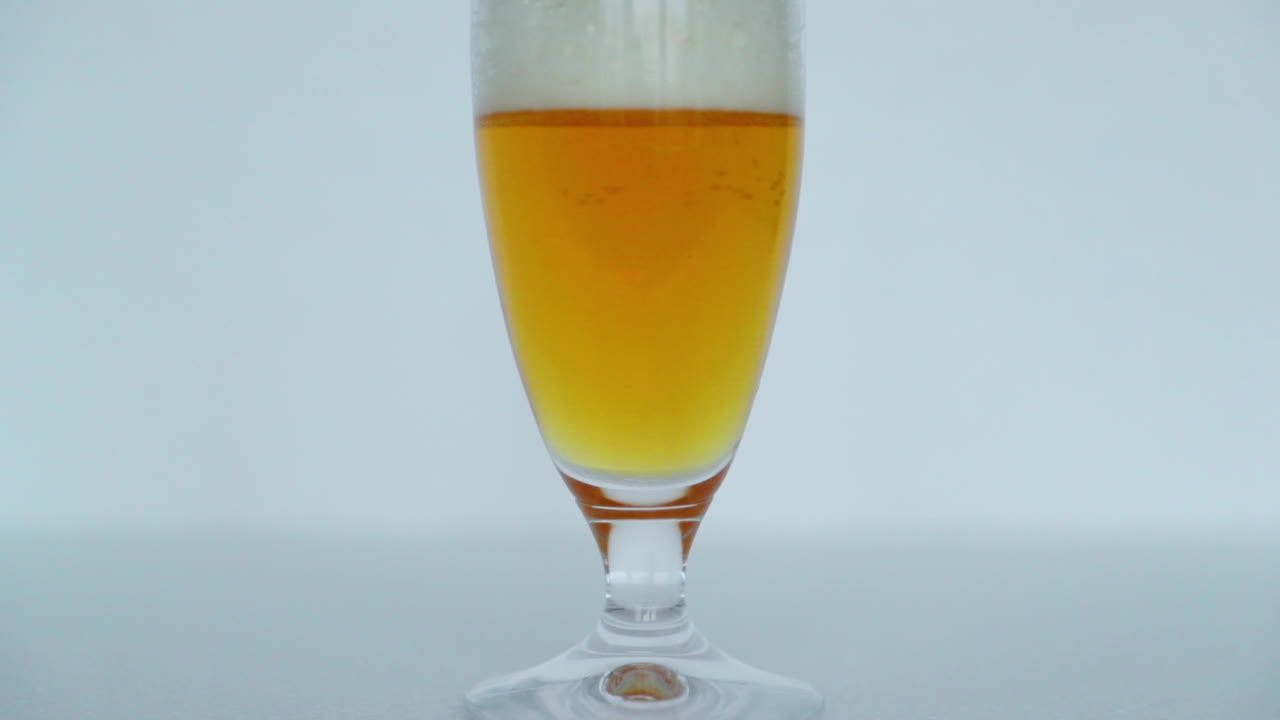 vista macro de primer plano de un vaso lleno de cerveza donde las burbujas se mueven lentamente hacia la parte superior de un vaso de hermoso color de cerveza con espuma en la parte superior en la captura de movimiento de velocidad normal
