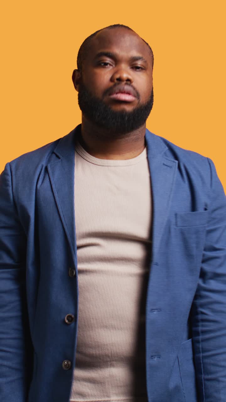 African American Man Shrugging with Confused Expression on Orange Background