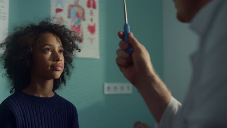 neurologist checking visual reflex african american teen kid in modern clinic.