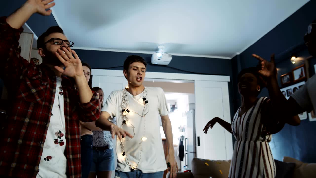 Happy millennial European male student having amazing fun dancing with friends at multiethnic birthday party slow motion