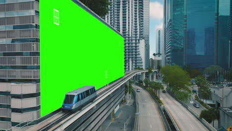Urban-train-passing-a-green-screen-placeholder-wall-in-a-modern-city---3D-render