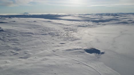 mountain road covered in snow on a shore of frozen lake in southern norway