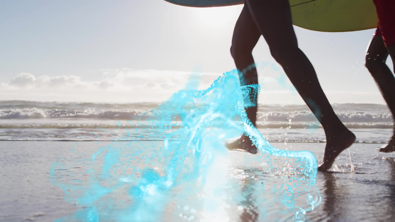 Two surfers running into ocean on beach, using technology with teal particles swirling around legs