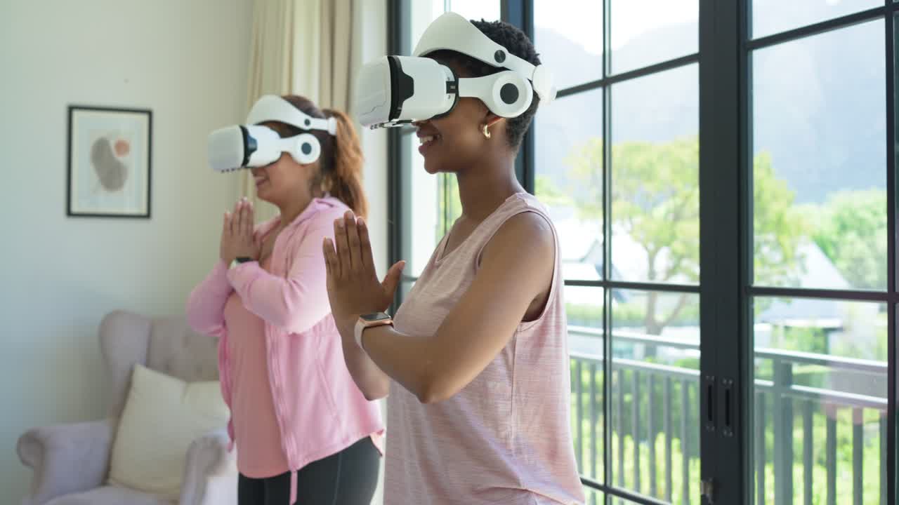 Due amiche adulte, con visori VR, praticano un esercizio guidato in soggiorno, in equilibrio.