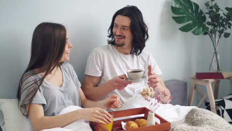 pareja disfrutando del desayuno en la cama