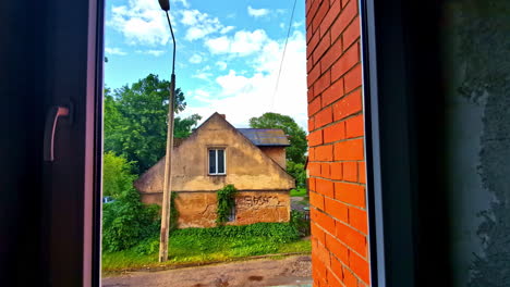 old rustic house overgrown with ivy seen through window frame from dark room