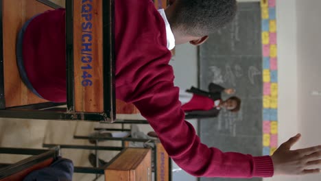 male student raising a hand and standing to answer in an african classroom in uganda