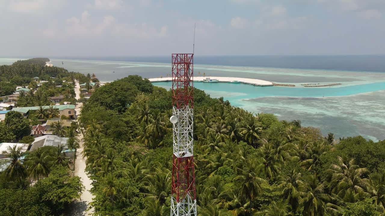 una torre celular alta se encuentra en una ciudad en el océano rodeada de árboles verdes contra un hermoso cielo