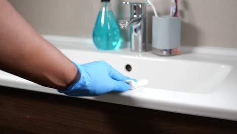 person cleaning a bathroom sink with disinfecting wipe