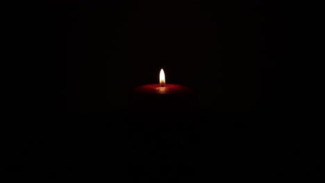 a single candle flame flickers in a dark room