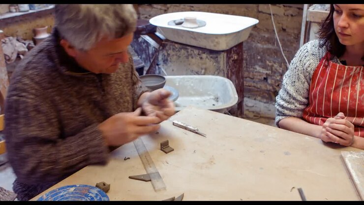 Potter teaching his colleague to mold the clay
